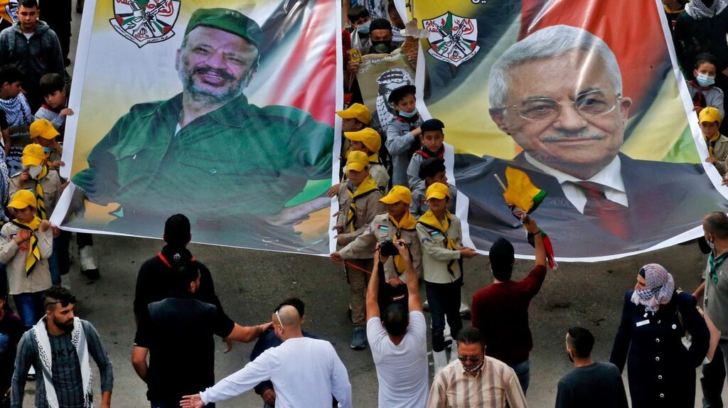 Palestinian Fateh movement supporters carry portraits of their current leader Mahmud Abbas (R) and his late predecessor Yasser Arafat (L) during a march to mark the 16th anniversary of Arafat's death in the village of Dura, near the West Bank city of Hebron 