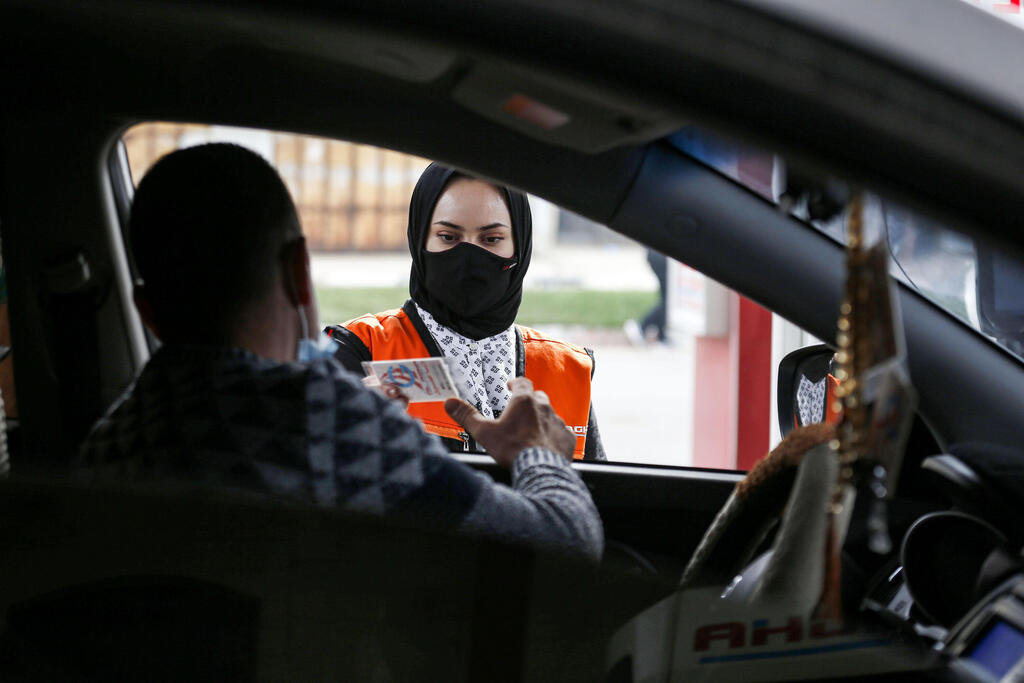 Salma al-Najjar, a 16-year-old Palestinian who works at a petrol station to help her family with income, hands over a card to the driver of a vehicle in Khan Yunis in southern Gaza Strip 
