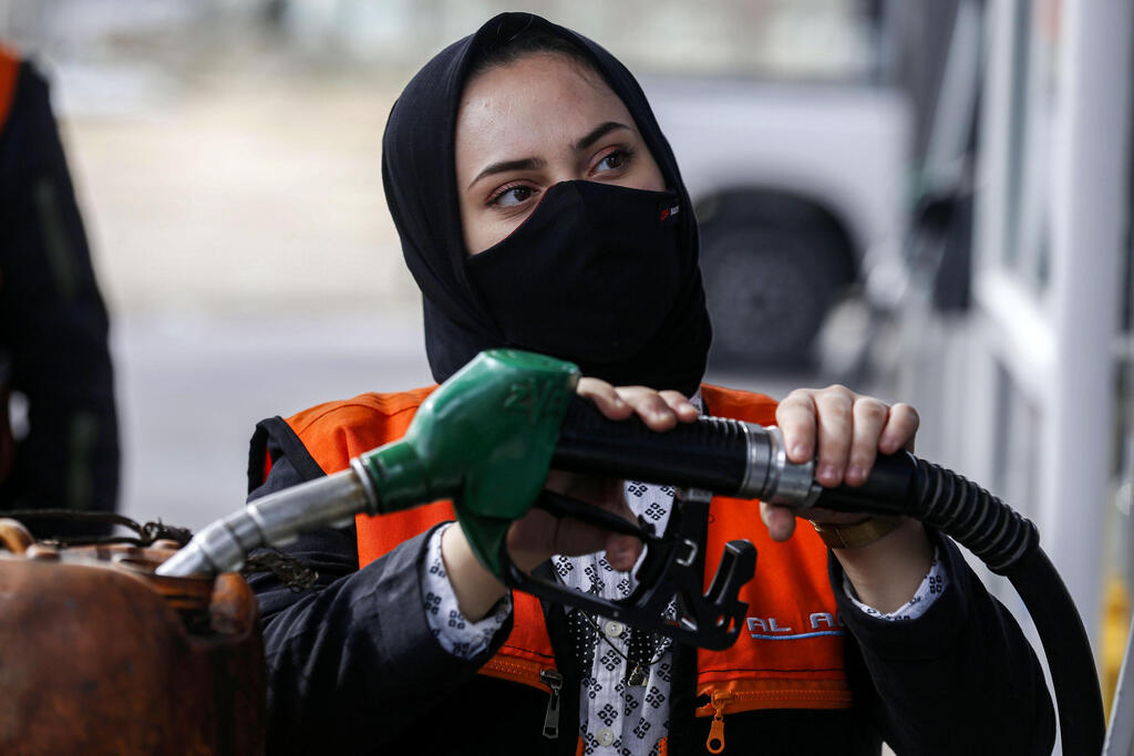 Salma al-Najjar, a 16-year-old Palestinian who works at a petrol station to help her family with income, adds fuel into a jerrycan in Khan Yunis in southern Gaza Strip 