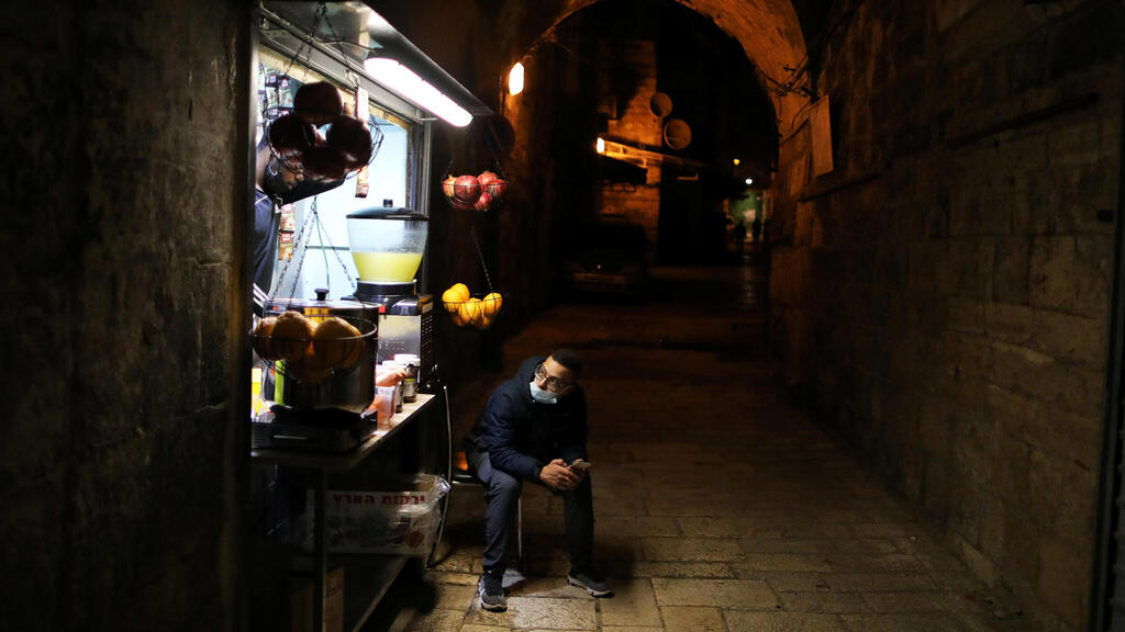 Luai al-Zarba, juice bar owner, chats to a Palestinian youth wearing a protective face in Jerusalem's Old City mask amid coronavirus crisis 