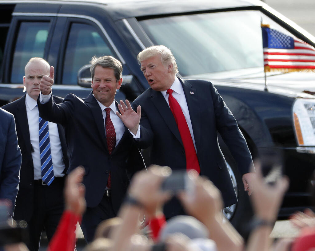 then-Georgia Republican gubernatorial candidate Brian Kemp, left, walks with President Donald Trump as Trump arrives for a rally in Macon , Ga. 