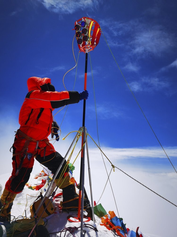 a member of a Chinese surveying team sets up a survey equipment on the summit of Mount Everest 