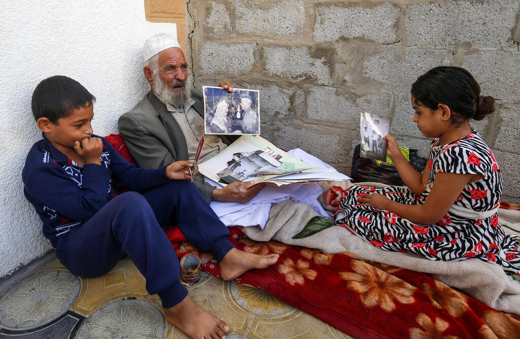 Iranian Qassem Sheyasi shows a photo of himself with longtime Palestinian leader Yasser Arafat as two of his children sit by his side in his house in Khan Yunis 
