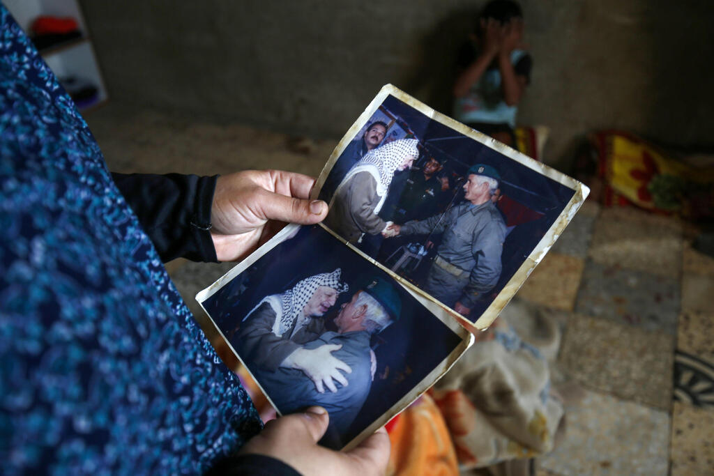 Mona Sheyasi, daughter of Iranian Qassem Sheyasi holds pictures of her father and longtime Palestinian leader Yasser Arafat 