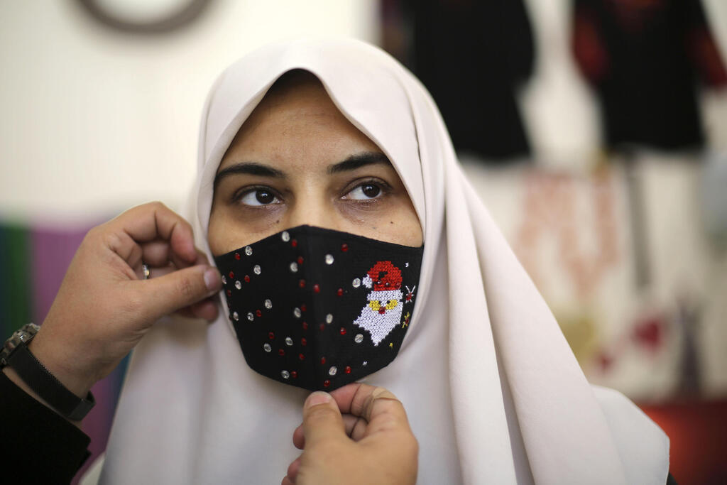 A Palestinian woman tries a Christmas-themed mask in Gaza City