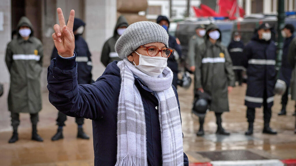 A woman flashes the victory sign while security forces block an avenue in front of Morocco's parliament building to stop a protest against the resumption of relations with Israel