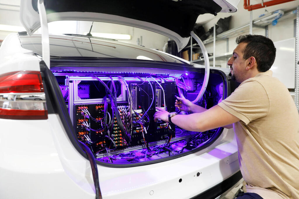 A worker tends to systems in the back of a Mobileye autonomous driving test vehicle, at the Mobileye headquarters in Jerusalem 