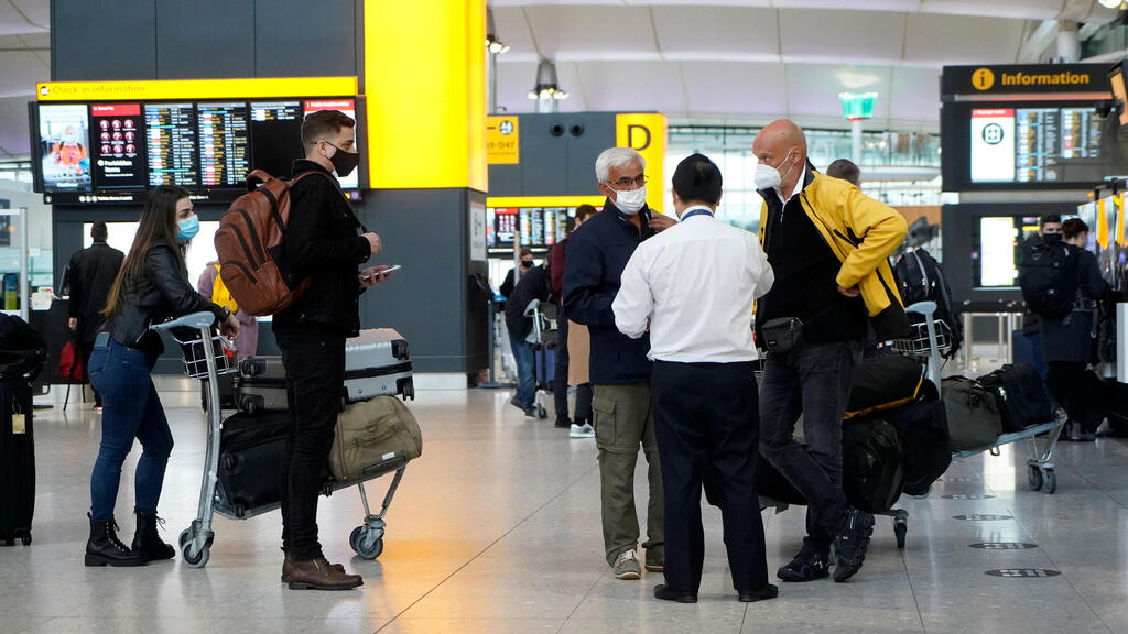 Travellers wearing a face mask or covering due to the COVID-19 pandemic, stand at check-in desks at Terminal 2 of Heathrow Airport in west London on December 21, 2020, as a string of countries around the world banned travellers arriving from the UK, due to the rapid spread of a new, more-infectious coronavirus strain