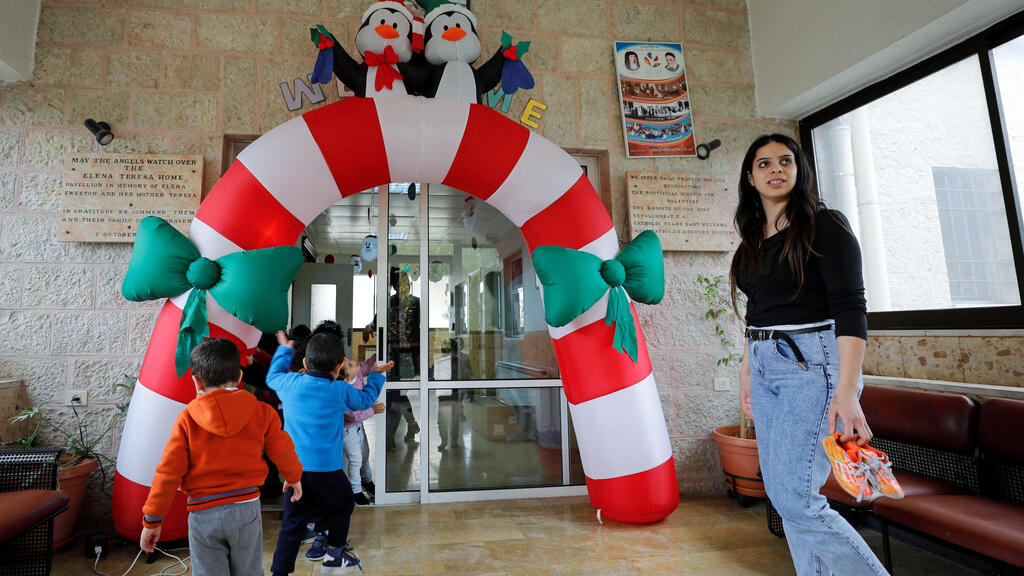 A staff member looks on as children play at The Creche, a house sheltering children, in Bethlehem 
