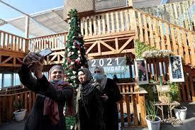 Gazan residents pose for pictures next to a Christmas tree in Gaza 