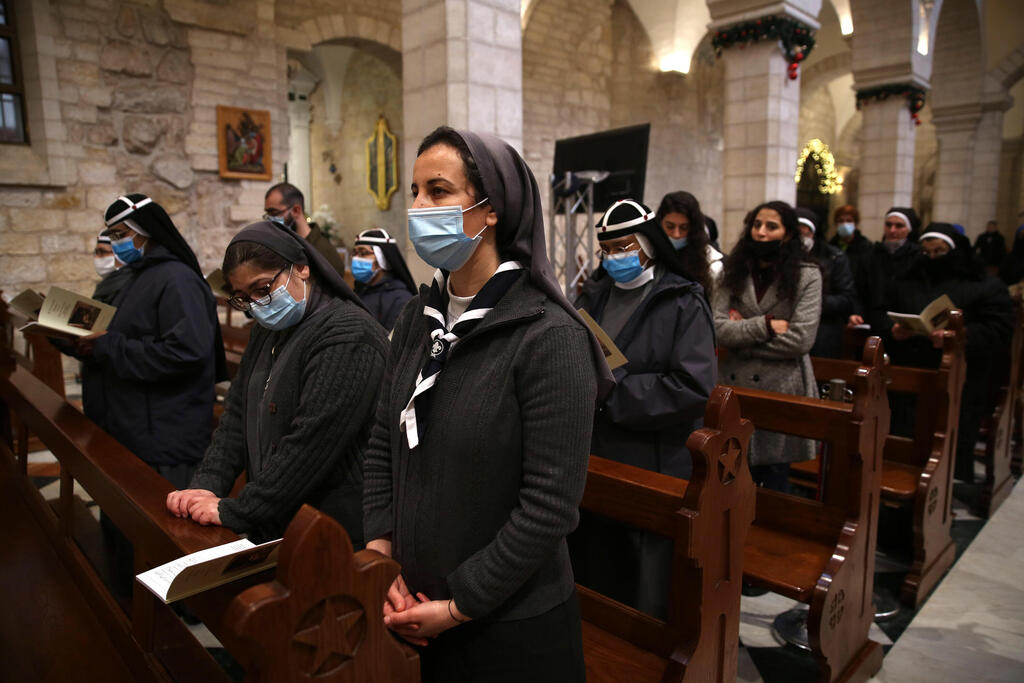 Nuns and people pray as they take part in a mass at the Church of Nativity in the West Bank town of Bethlehem