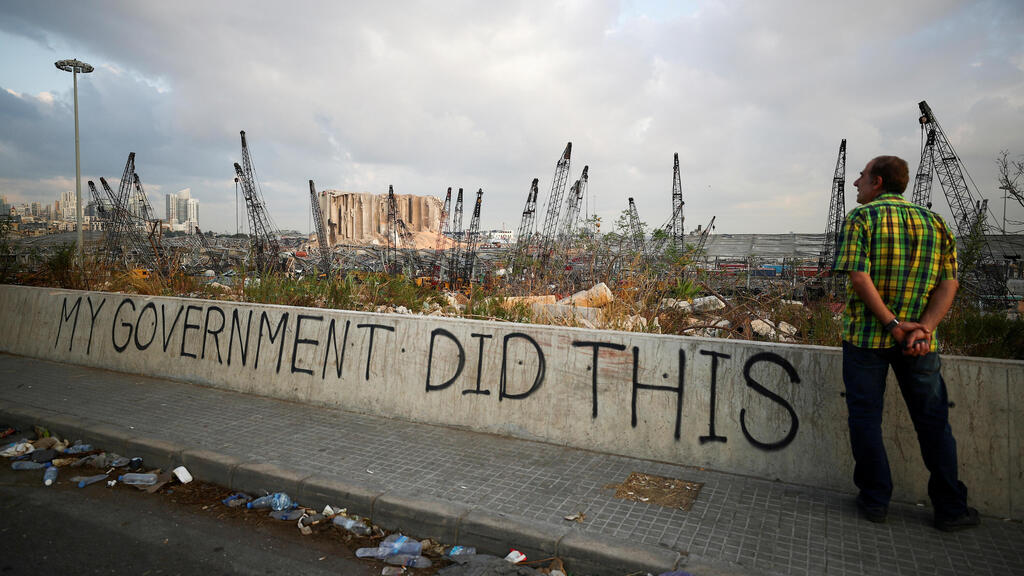 A man stands next to graffiti at the damaged port area in the aftermath of a massive explosion in Beirut, Lebanon 