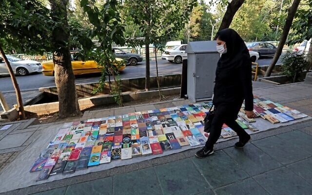 A woman walks past books displayed for sale along a pavement on Enqelab (Revolution) street in Iran’s capital Tehran 