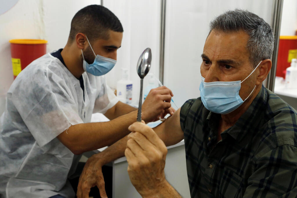 Celebrity mystic Uri Geller holds a spoon as he performs his spoon-bending trick for medical staff while receiving a vaccination against the coronavirus disease (COVID-19), in Jaffa, near Tel Aviv, Israel 