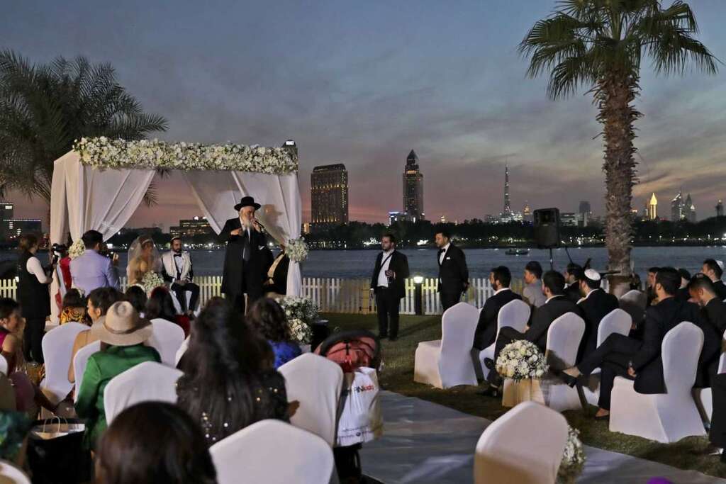A rabbi officiates under a traditional Jewish wedding canopy during marriage ceremony of the Israeli couple Noemie Azerad, left sited under the canopy, and Simon David Benhamou, at a hotel in Dubai, United Arab Emirates 