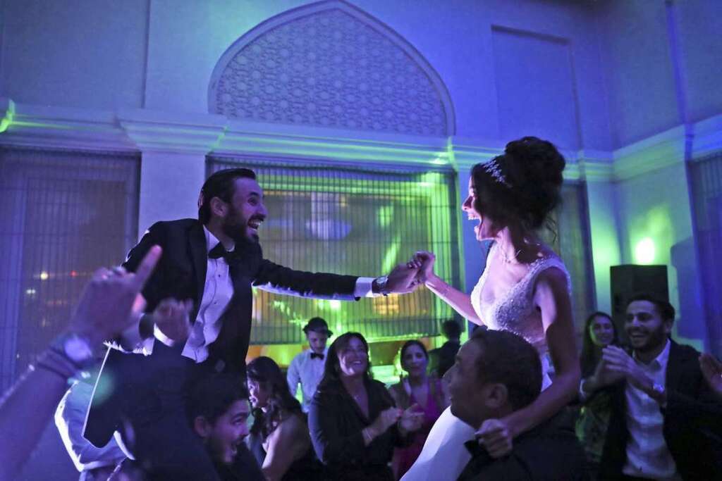 Israeli couple Noemie Azerad, right, and her husband Simon David Benhamou grasp each others hands on the shoulders of skullcap-wearing groomsmen during their wedding party at a hotel in Dubai, United Arab Emirates 