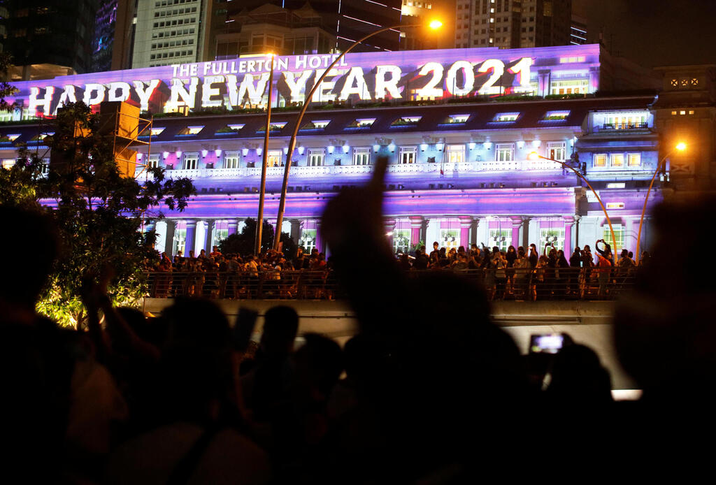 People watch a lights show, as the traditional New Year's Eve fireworks are cancelled due to the coronavirus disease (COVID-19) outbreak, at Marina Bay in Singapore