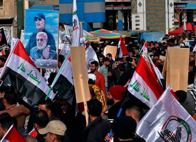 Supporters of the Popular Mobilization Forces hold a poster of Abu Mahdi al-Muhandis, deputy commander of the Popular Mobilization Forces, front, and General Qassem Soleimani, head of Iran's Quds force during a protest, in Tahrir Square, Iraq 