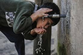 A boy drinking water out of a tap in Gaza 