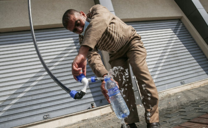 A Palestinian man filling a bottle with water produced by the Watergen technology in Gaza 