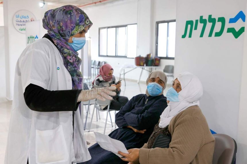A healthcare worker speaks to an Arab Israeli woman before giving her a Covid-19 vaccine 