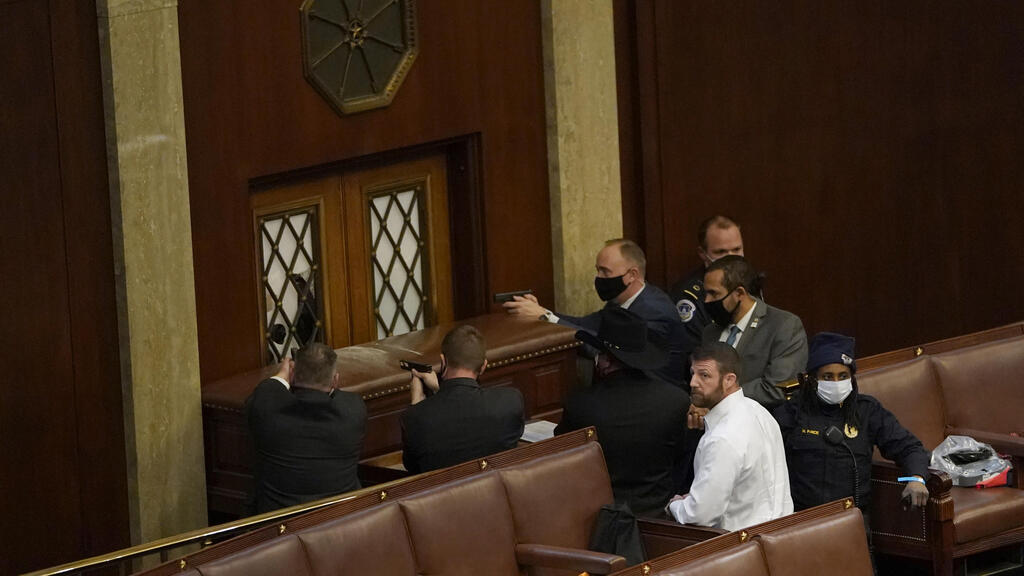 U.S. Capitol police officers point their guns at a door that was vandalized in the House Chamber during a joint session of Congress 