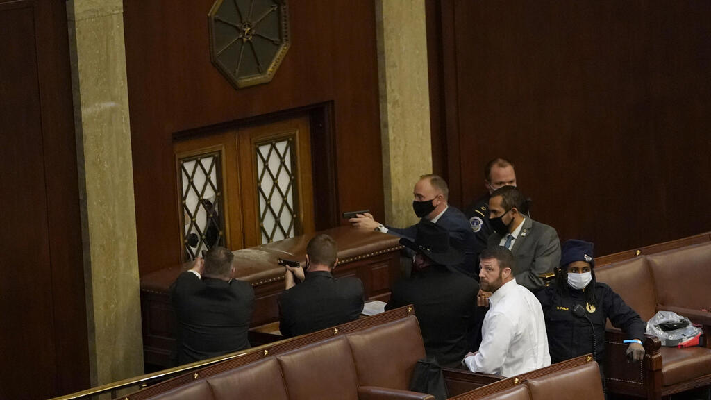 U.S. Capitol police officers point their guns at a door that was vandalized in the House Chamber during a joint session of Congress 