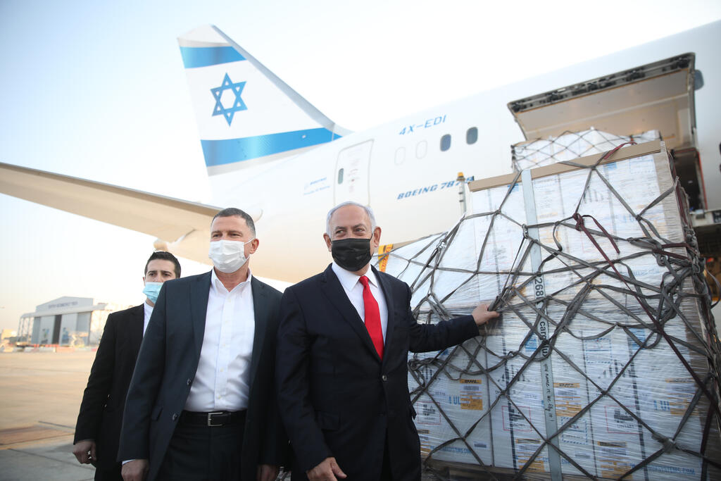Health Minister Yuli Edelstein and Prime Minister Benjamin Netanyahu stand next to a shipment of Pfizer vaccines as they arrived at Ben-Gurion Airport, Jan. 2021 