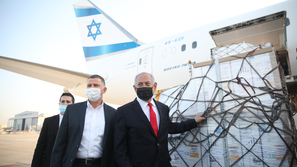 Benjamin Netanyahu and Health Minister Yuli Edelstein greet a plane carrying Pfizer vaccines as it arrives at Ben-Gurion Airport 