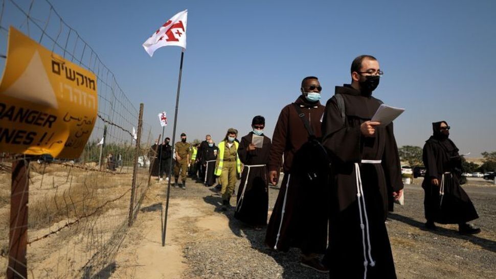 Pilgrims march towards the Jordan River to participate in a baptism ceremony at the Qasr el-Yahud site, near Jericho, in the West Bank