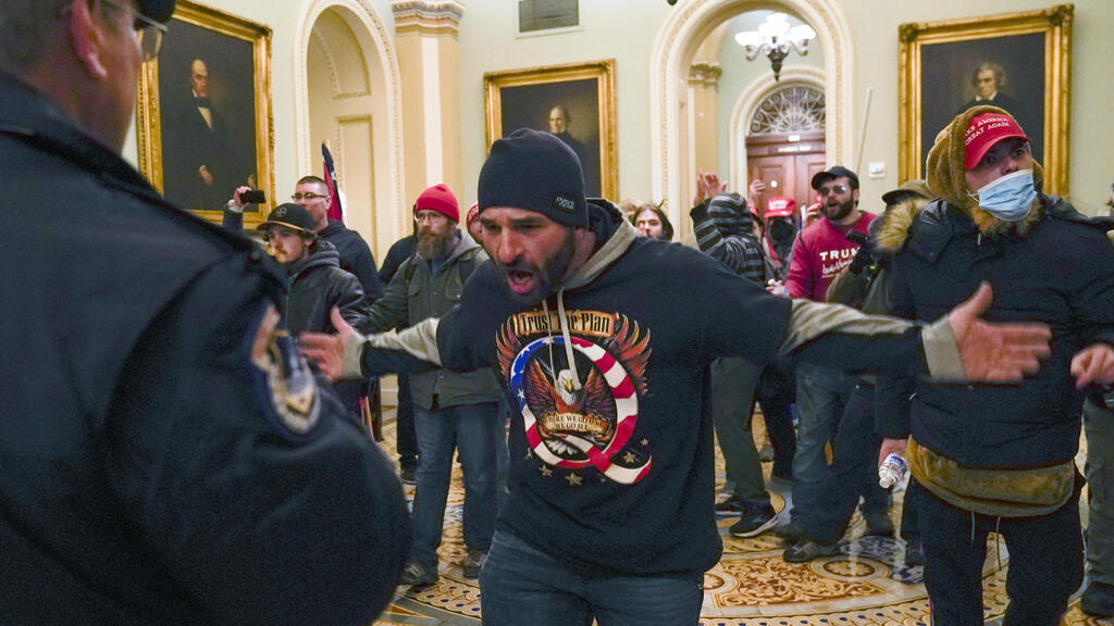 Iowan Trump supporter Doug Jensen, clad in a QAnon sweatshirt, gestures to a Capitol Police officer after storming the building on Jan. 6, 2021 