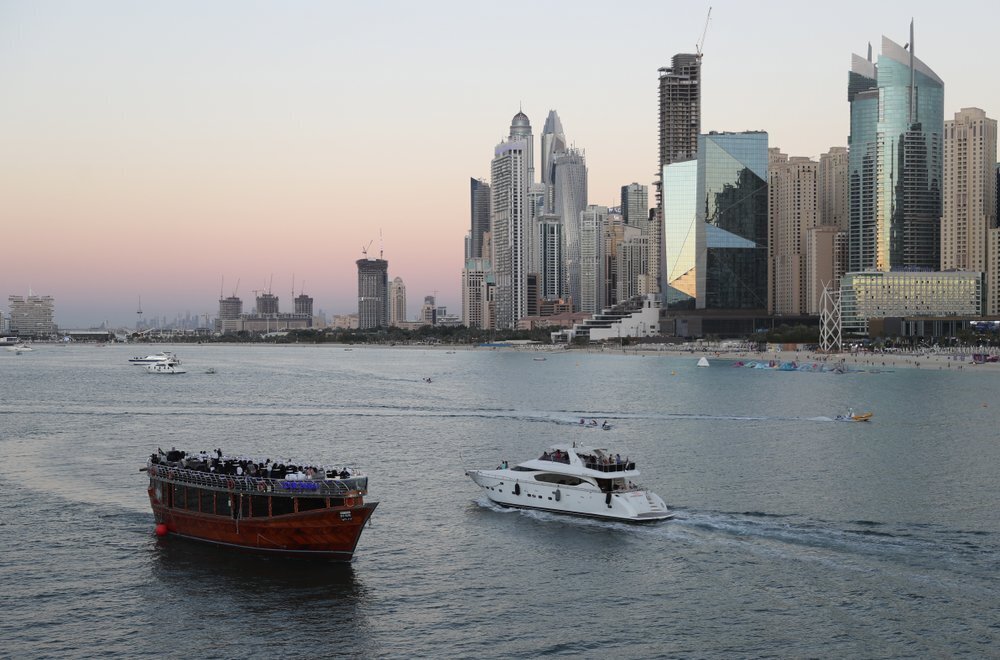 Tourists on a yacht as they pass a traditional dhow serving a dinner cruise, in Dubai, United Arab Emirates 