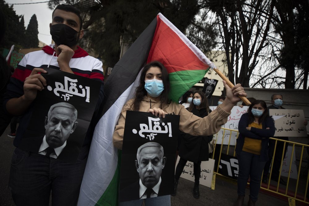 Palestinian protesters hold signs and flags during a demonstration against a visit of Israeli Prime Minister Benjamin Netanyahu to the northern Arab city of Nazareth 