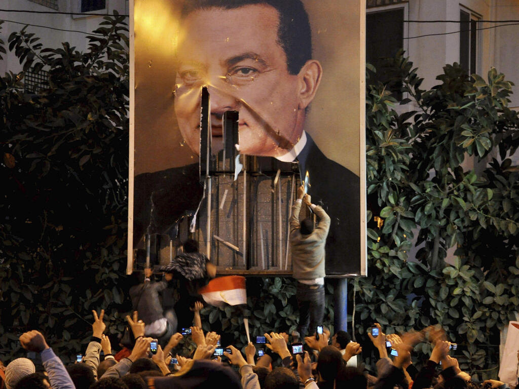  demonstrators deface a poster of Egyptian President Hosni Mubarak in Alexandria, Egypt