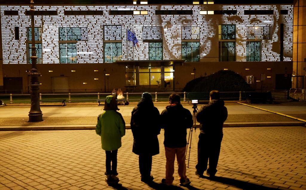 People watch at a light installation called #everynamecounts projecting names of victims of the Nazi regime on the facade of the French embassy to remember the victims ahead the Holocaust Memorial Day in Berlin, Germany 