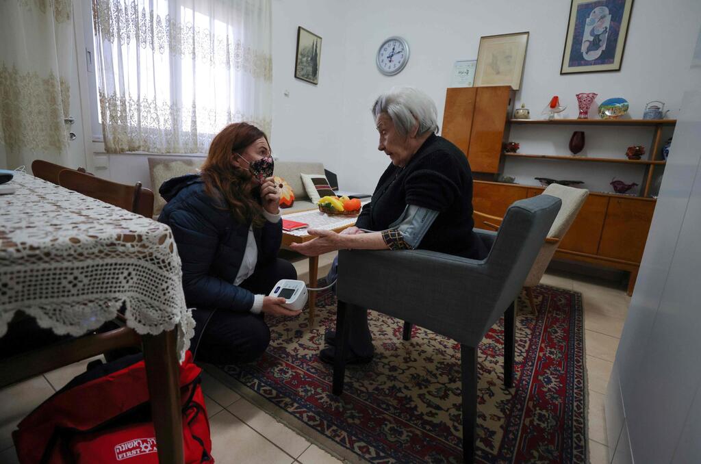 Holocaust survivor Miriam Linia receives medical home support from a volunteer on the premises of Israel's Yad Ezer La-Haver foundation, which supports survivors of the Holocaust by providing them food as well as medical and psychological assistance, in the northern port city of Haifa 