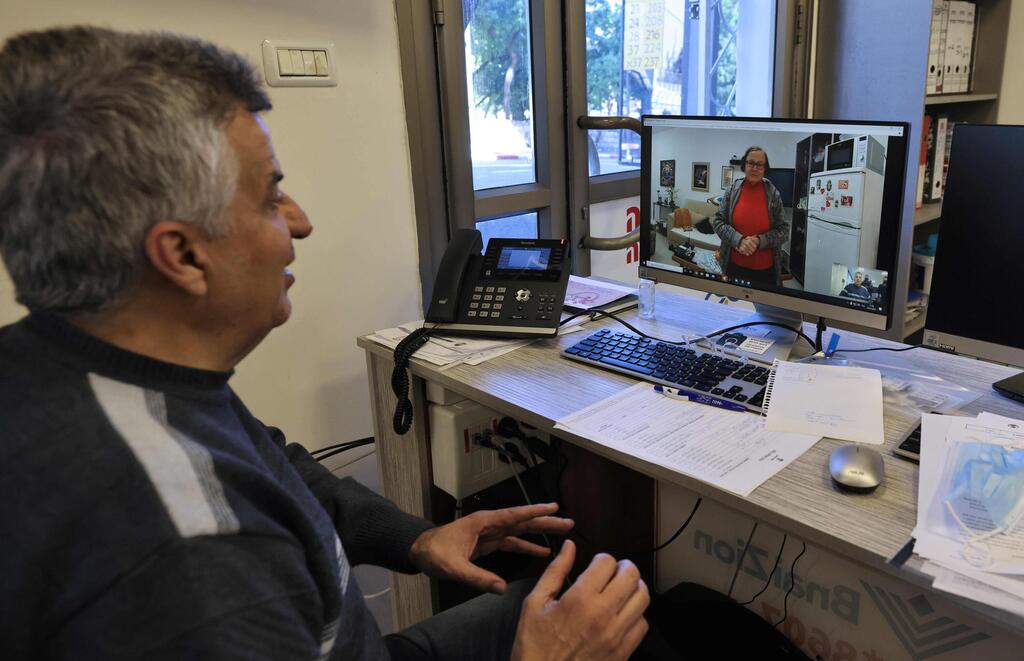 Holocaust survivor Naomie Lichthaus, 86, talks via video call with Shimon Shabag, siting at the call centre of Israel's Yad Ezer La-Haver foundation, which supports survivors of the Holocaust by providing them food as well as medical and psychological assistance, in the northern port city of Haifa 