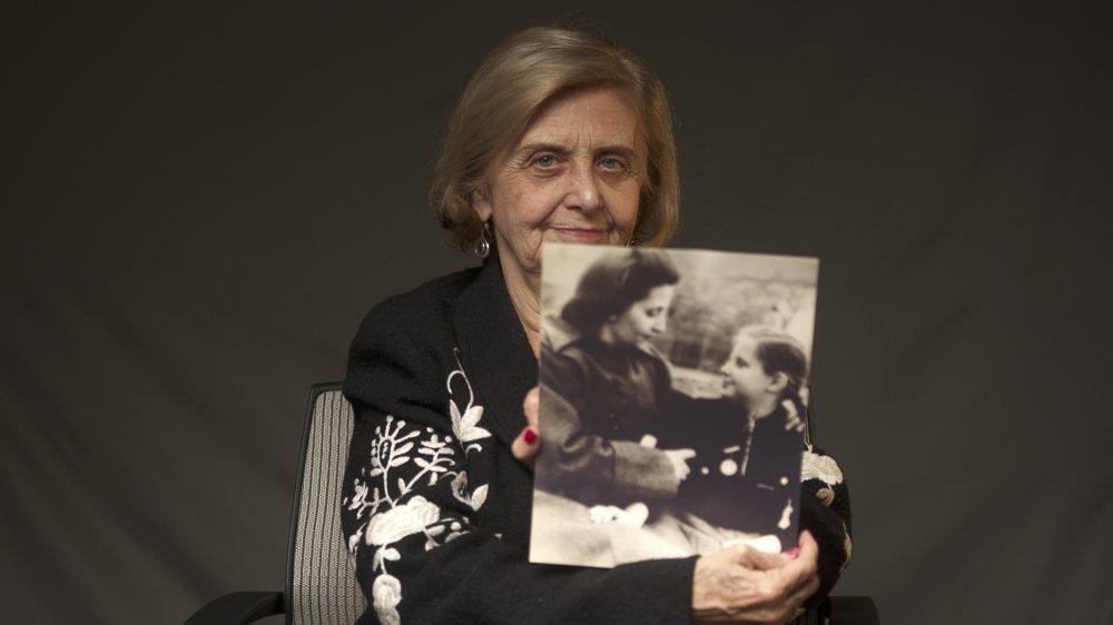 Tova Friedman, an 82-year-old Polish-born Holocaust survivor holding a photograph of herself as a child with her mother, who also survived the Nazi death camp Auschwitz 