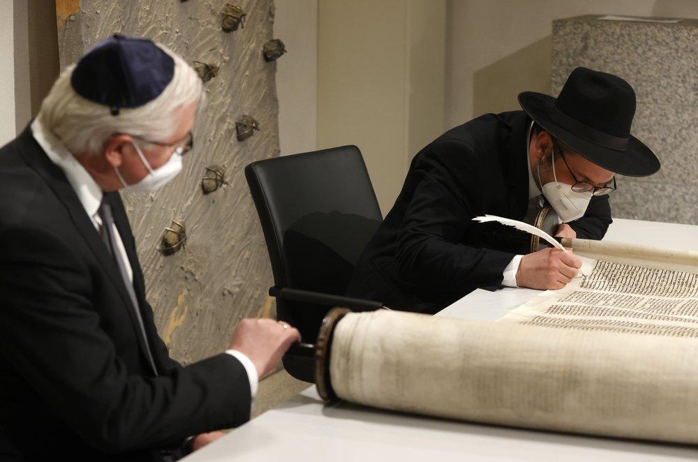 German President Frank-Walter Steinmeier, right, and Rabbi Shaul Nekrich, right, take part in a ceremony at the Reichstag building in Berlin, Germany, Wednesday, Jan. 27, 2021 to complete the historic Sulzbach Torah Scroll from 1792, rediscovered in 2013 and just restored. The ceremony takes place on the International Holocaust Remembrance Day 