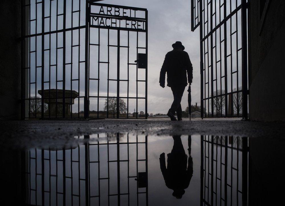 a man walks through the gate of the Sachsenhausen Nazi death camp with the phrase 'Arbeit macht frei' (work sets you free) during International Holocaust Remembrance Day in Oranienburg, about 30 kilometers (18 miles), north of Berlin, Germany 