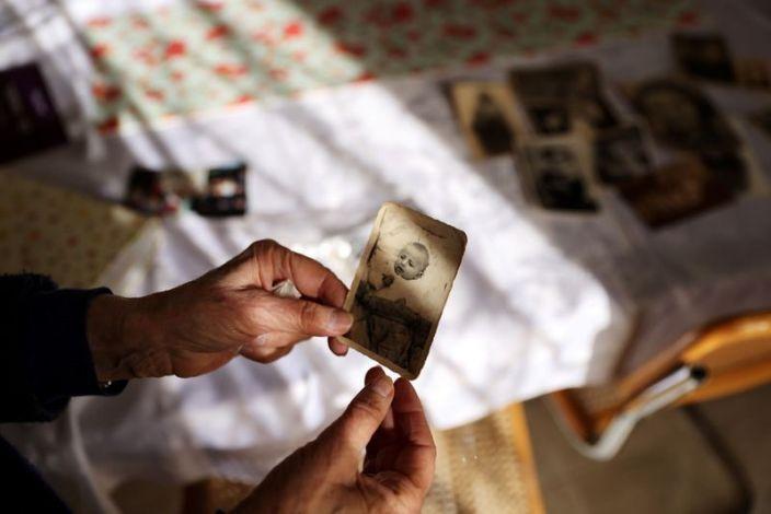 Holocaust survivor Leah Nebenzahl holds a photograph of herself 