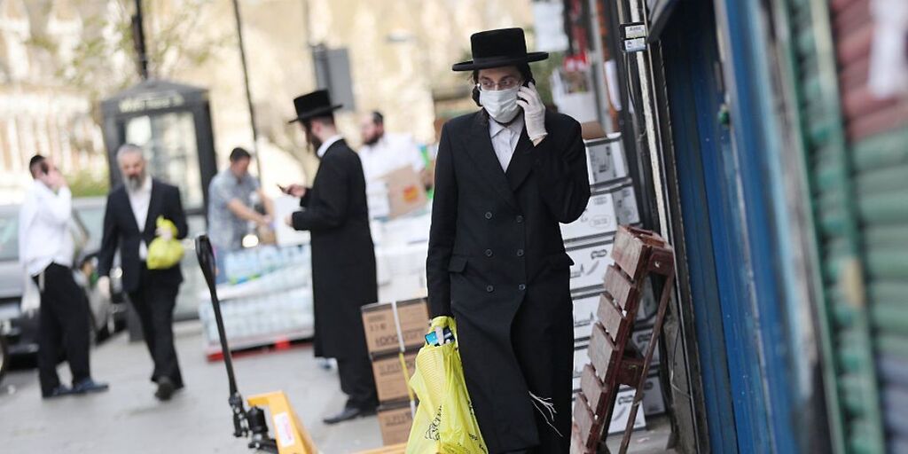 Ultra-Orthodox Jewish man donning protective face mask and gloves walking down London's Stamford Hill neighborhood during COVID-19 pandemic