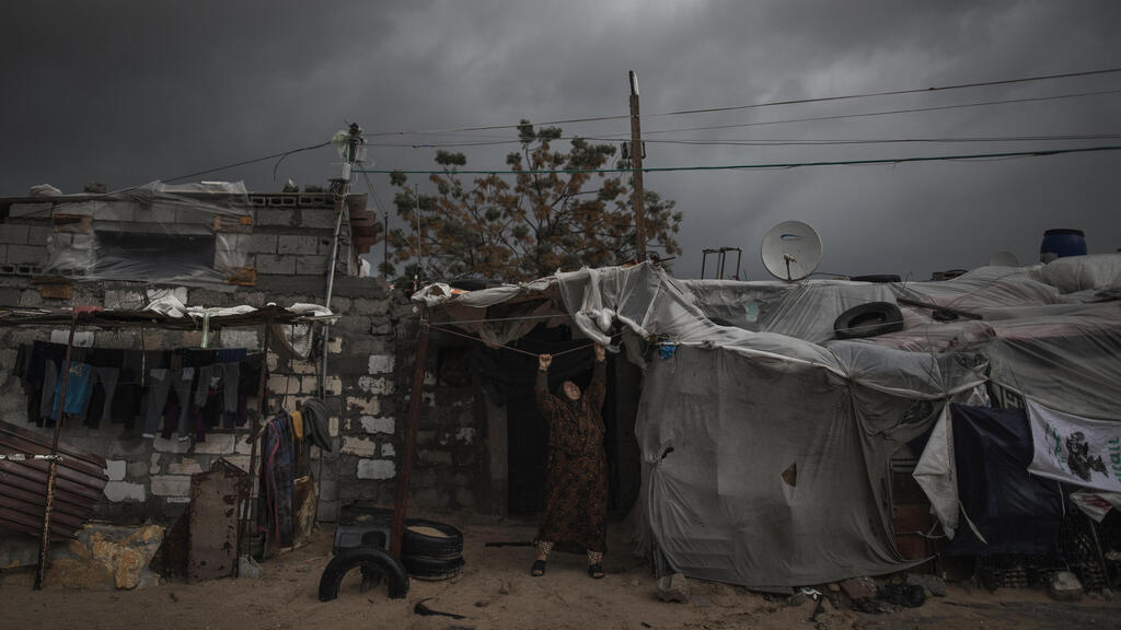 A Gaza woman adjusts a nylon cover on her home last month 