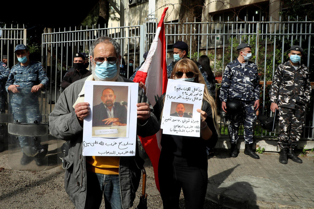 Protesters hold pictures of Lokman Slim outside the Justice Palace in Beirut after his killing, Feb. 4, 2021 