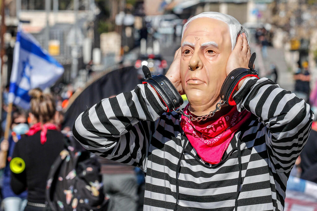 A demonstrator wearing a mask of Benjamin Netanyahu gestures during a protest outside Jerusalem District Court as the prime minister's corruption trial resumes, Feb. 8, 2021 