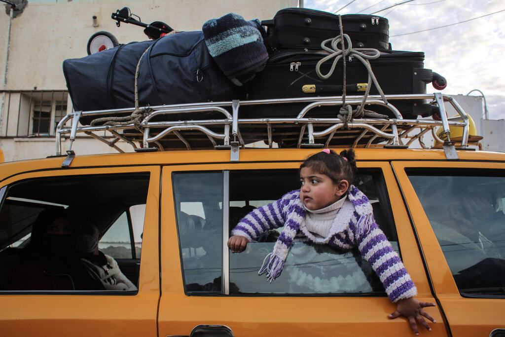 A girl looks on through the window of a vehicle whose top is loaded with suitcases, while waiting at the Rafah border crossing's departure area to travel from the Gaza Strip into Egypt 