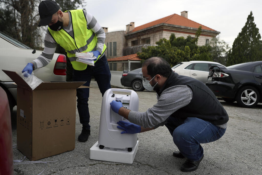 Baytna Baytak members unpack oxygen machine to be donated to an elderly COVID-19 patient in a village north of Beirut, Lebanon