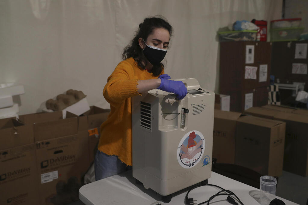 Member of Lebanese NGO Baytna Baytak, Gaelle Fenianos, sanitizes an oxygen machine before it is delivered to patients in need, in Beirut, Lebanon