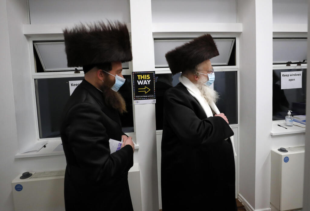 Two men from the Haredi Orthodox Jewish community arrive at an event to encourage vaccine uptake 