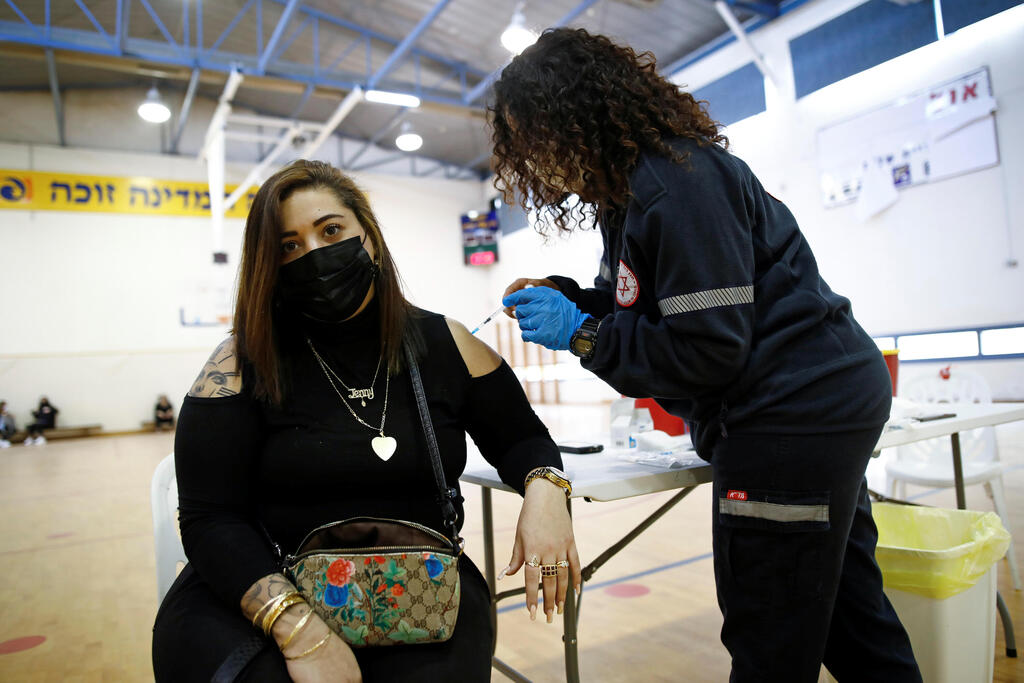 A woman is vaccinated against the coronavirus disease (COVID-19) at a temporary vaccination centre at a sports court in Tel Aviv 